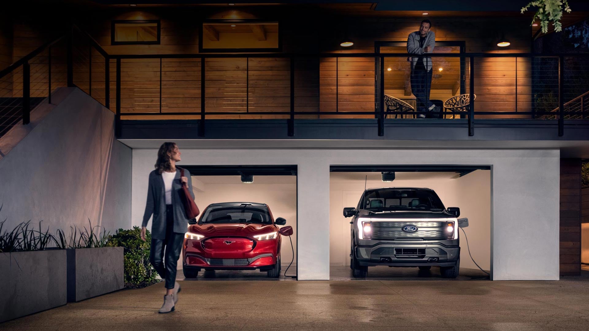 Woman walking out from home garage with a 2024 Mustang® Mach-E and Ford Lightning® truck in plugged-in and charging | Woodland Ford in Woodland CA
